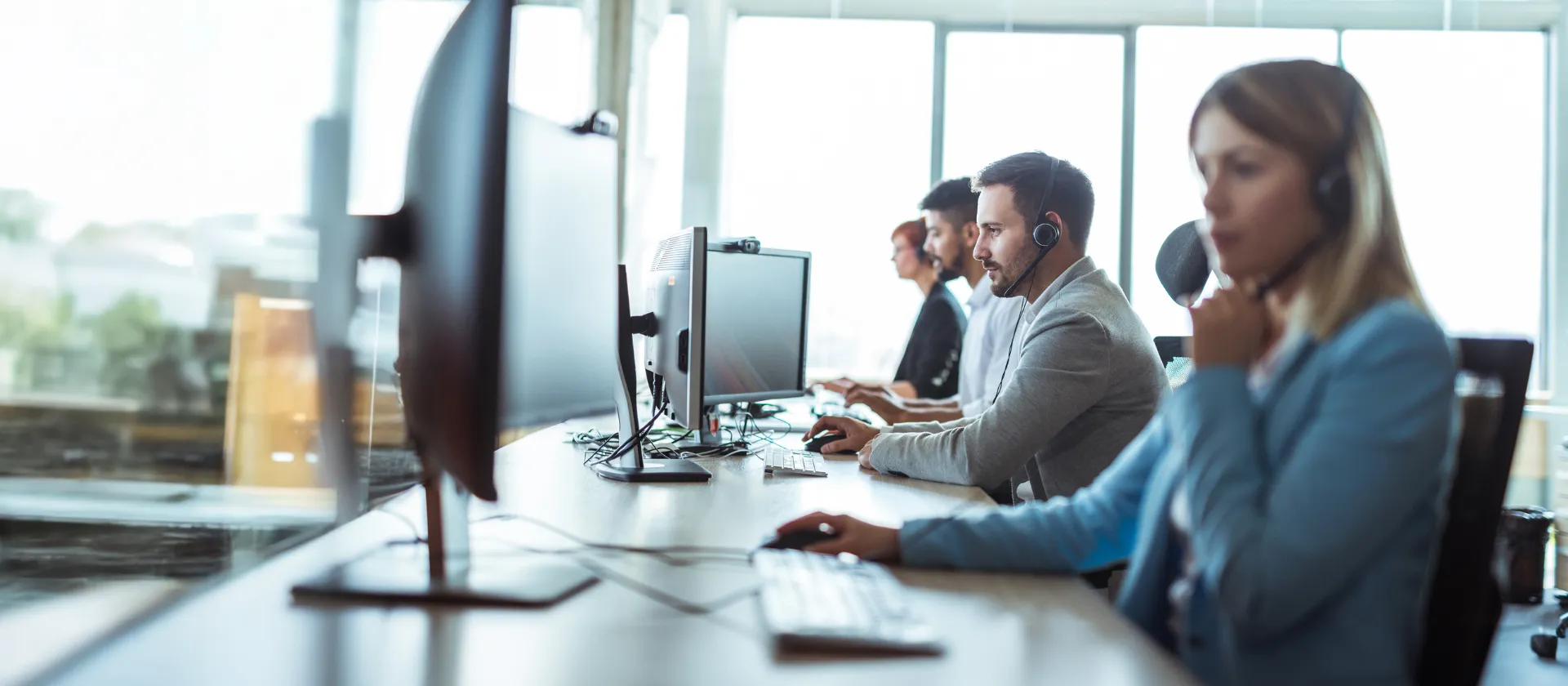 fpsl technical application management service representatives wearing headsets working on desktop computers in modern office.