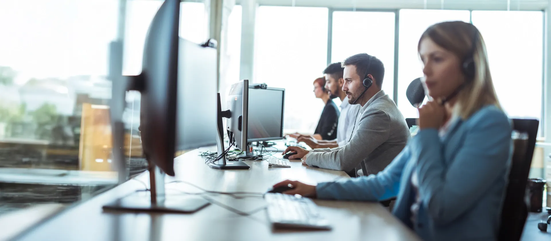 fpsl technical application management service representatives wearing headsets working on desktop computers in modern office.