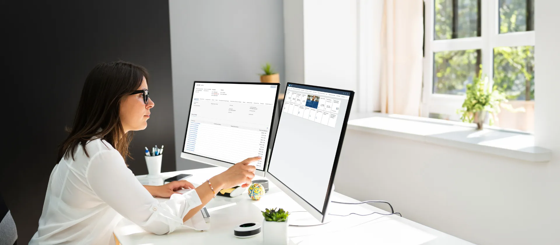 Professional working at desk on dual monitors displaying SAP FS-CD Collections and Disbursements dashboard and reporting tools