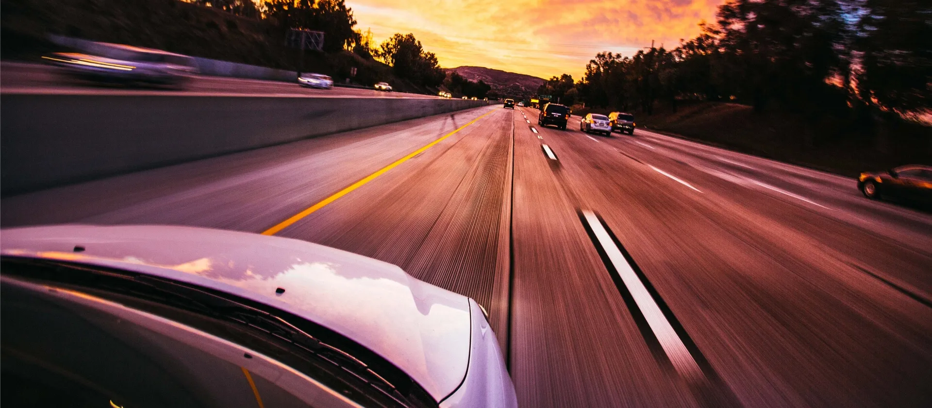Cars driving on a highway at sunset, symbolizing connected mobility, telematics, and smart transportation systems with msg.EDR
