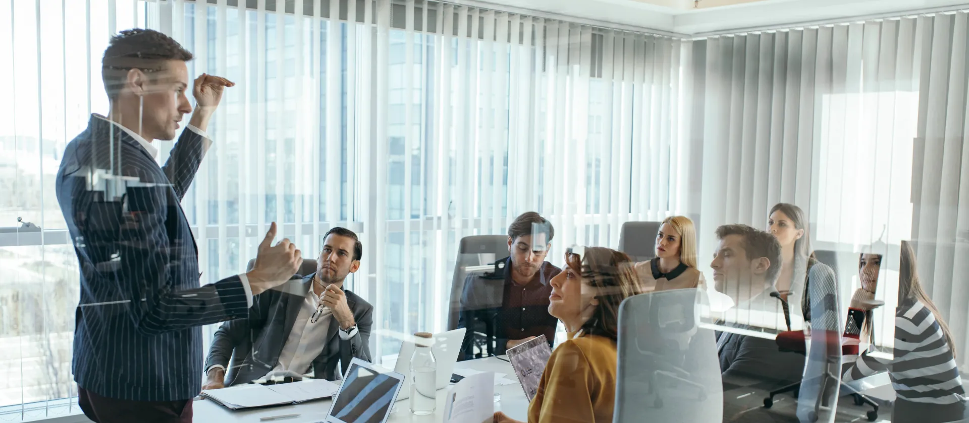 Business professional presenting to colleagues in a conference room meeting with laptops and documents for SAP Financial Products subledger enablement