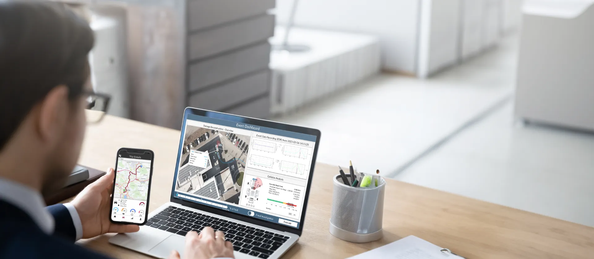Person using laptop and smartphone displaying msg IoTA dashboard with event data and location maps in an office setting.