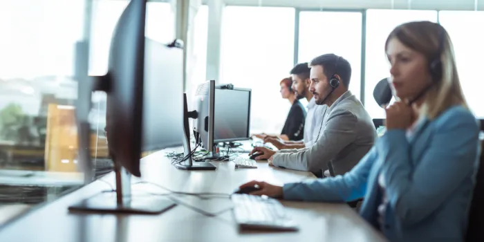 fpsl technical application management service representatives wearing headsets working on desktop computers in modern office.