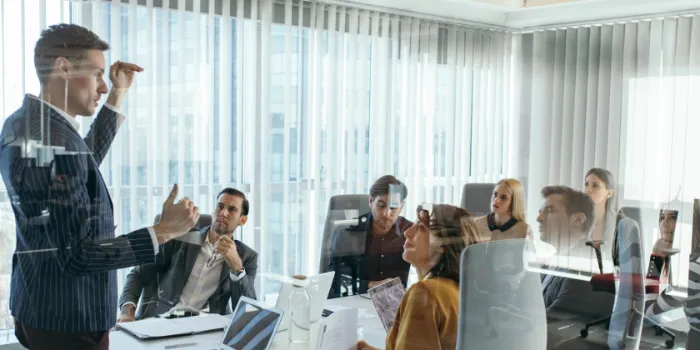Business professional presenting to colleagues in a conference room meeting with laptops and documents for SAP Financial Products subledger enablement