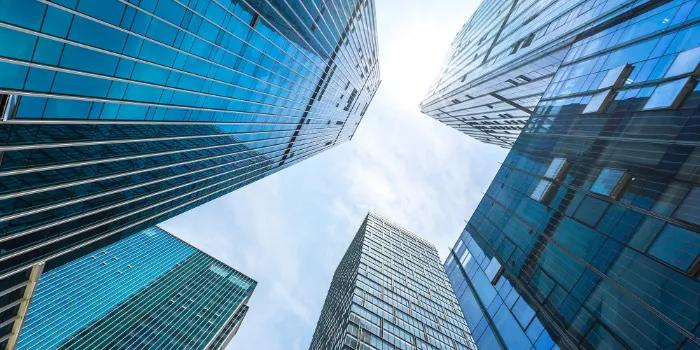View looking up at modern glass skyscrapers against a bright sky, symbolizing innovation, growth, and corporate vision.