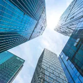 View looking up at modern glass skyscrapers against a bright sky, symbolizing innovation, growth, and corporate vision.