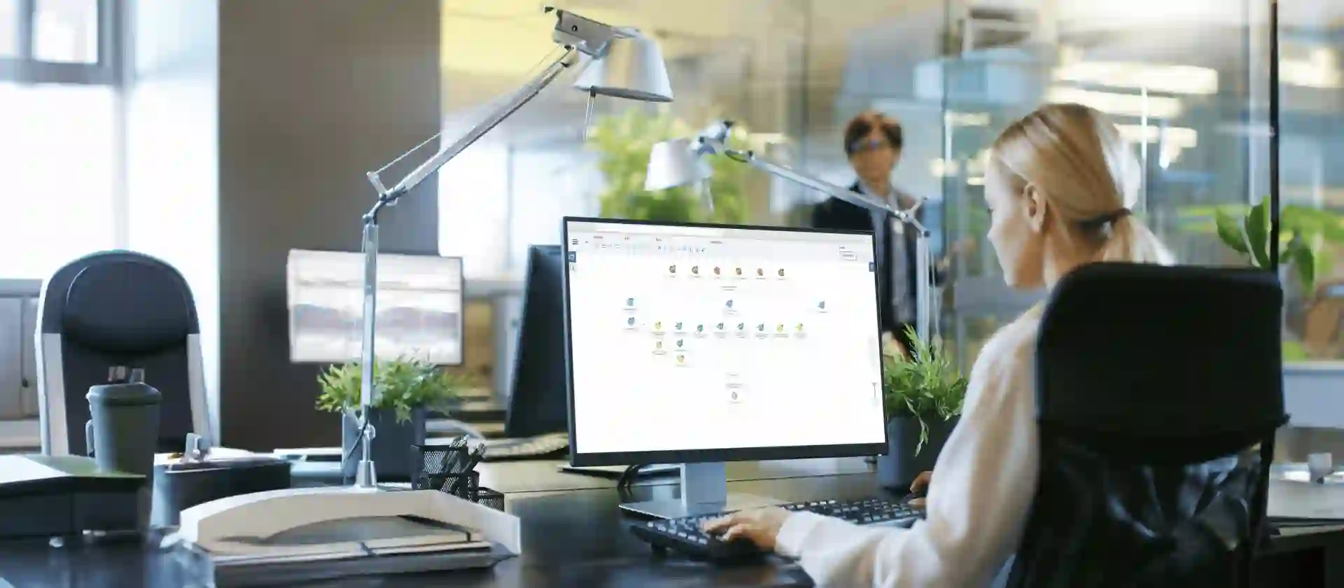Businesswoman working on desktop computer with SAP analytics software in modern office environment